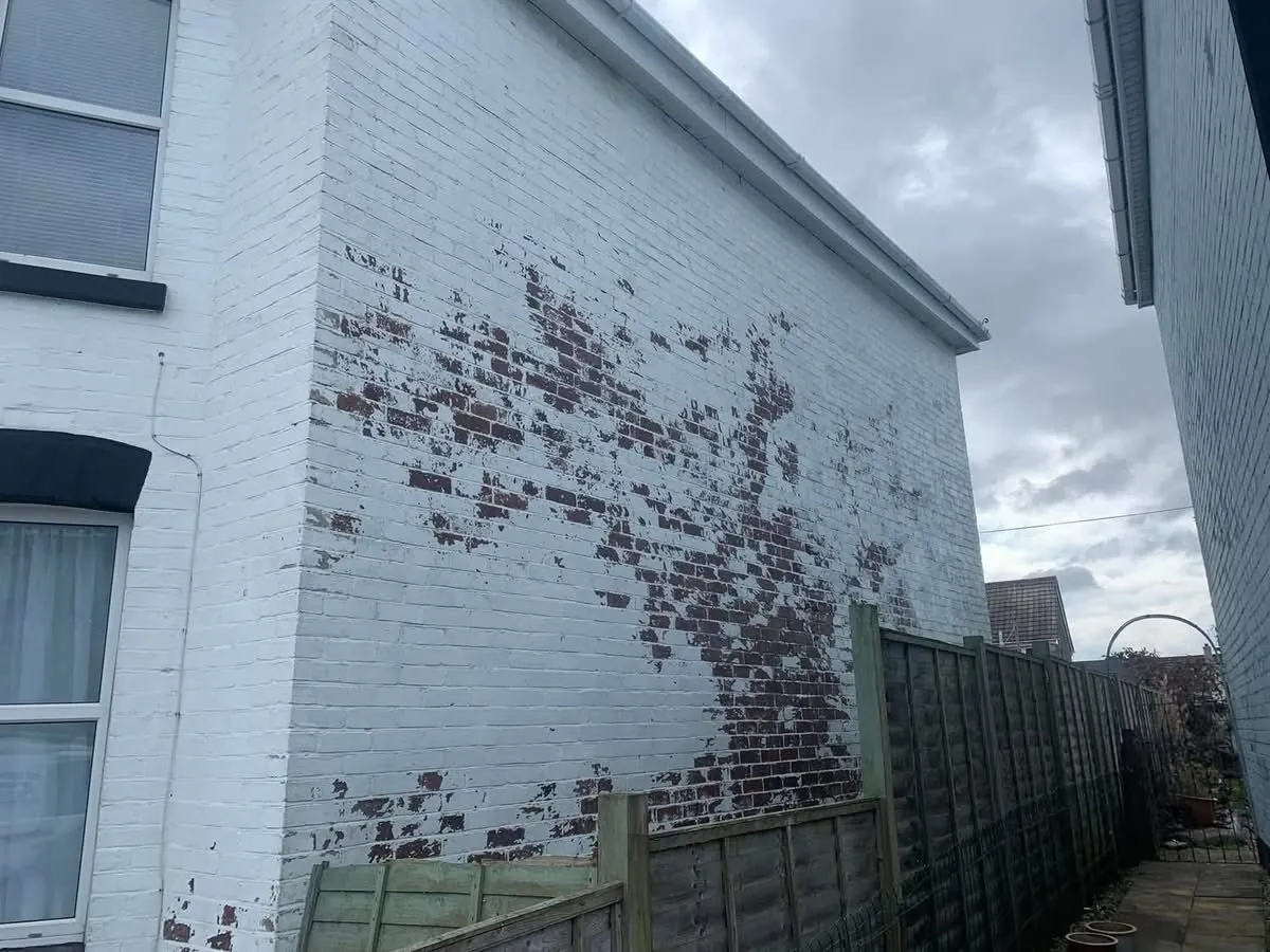 Peeling paint on a brick wall before redecoration in Lostwithiel